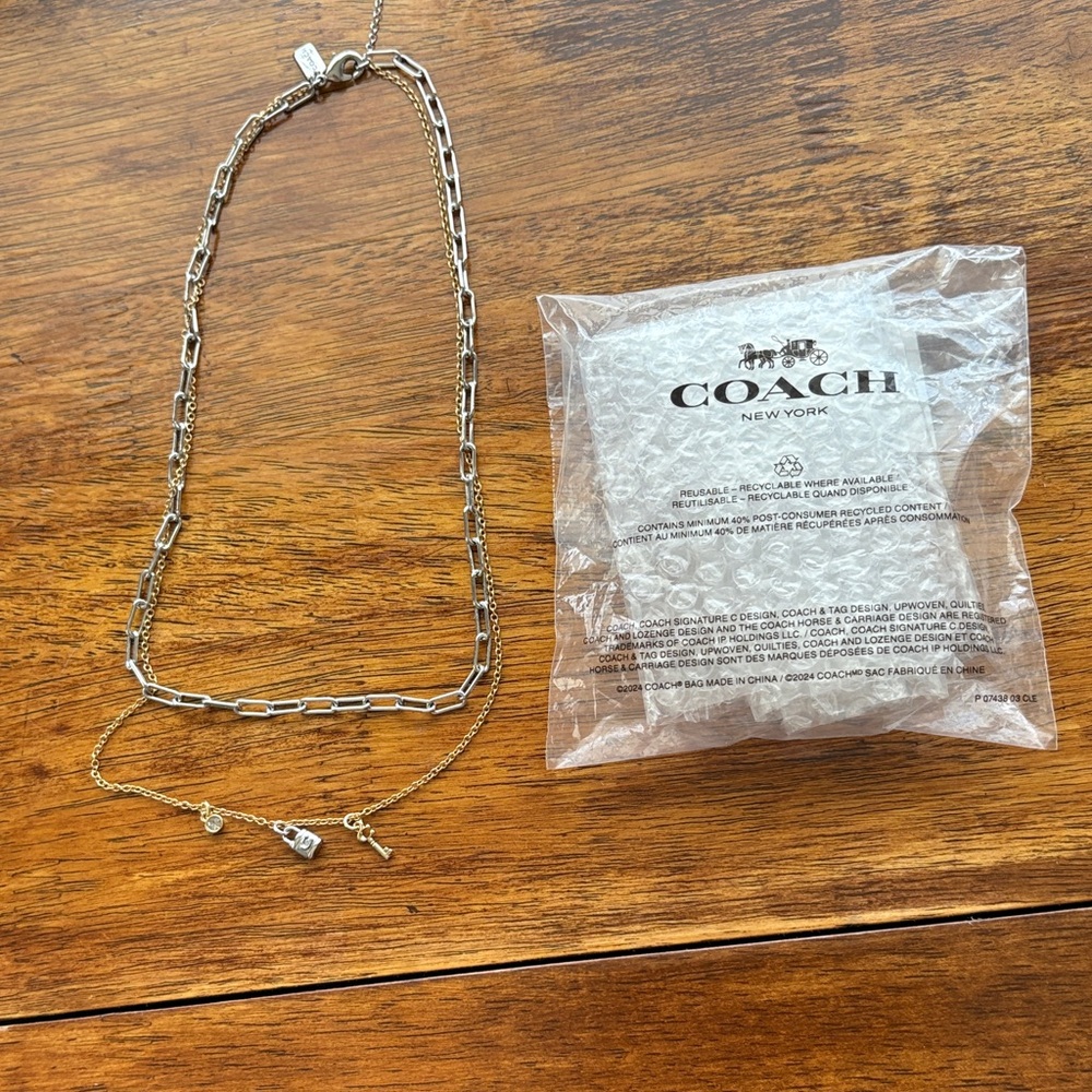 New Coach silver & gold paper clip necklace with 3 charms. Has a 3” extension